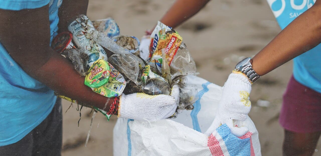 hands picking up plastic waste from the beach