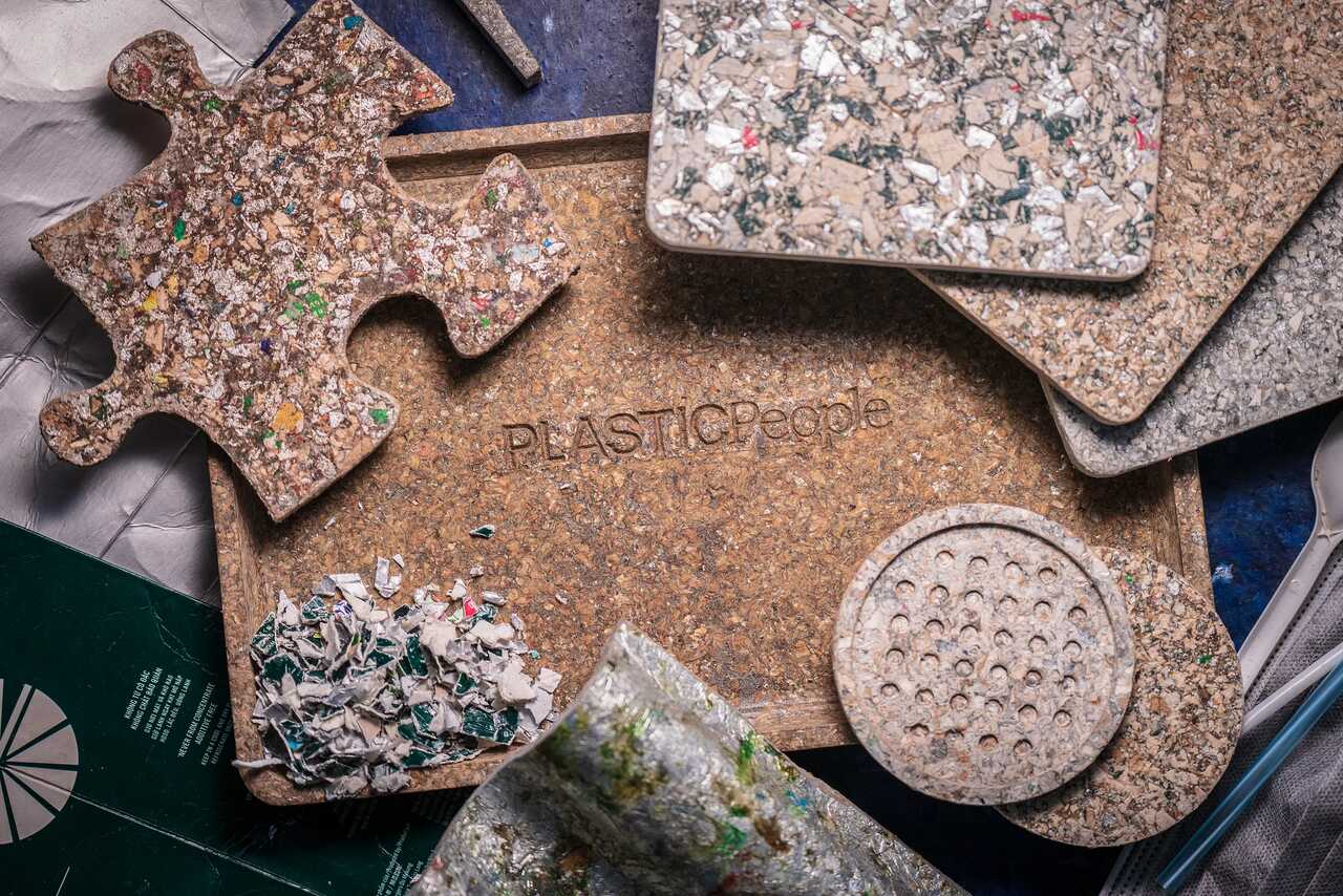 Recycled plastic products created by PLASTICPeople, featuring sustainable materials shaped into functional items like a puzzle piece, trays, and coasters. These products demonstrate how plastic waste can be transformed into high-quality, circular economy solutions.