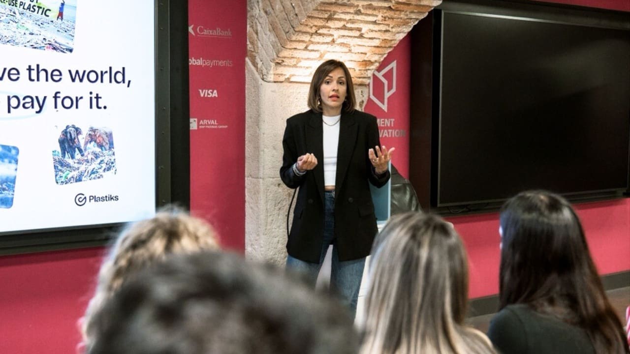 Ana Aguilar COO at Plastiks, speaks at a sustainability conference. Behind her, a presentation slide with Plastiks branding discusses plastic recovery and environmental impact.